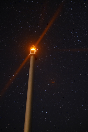 A lighthouse shining in the dark sky